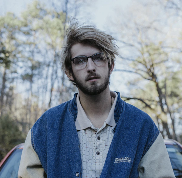 Retrato de Júlia Mendes, sorrindo em frente a uma parede de tijolos